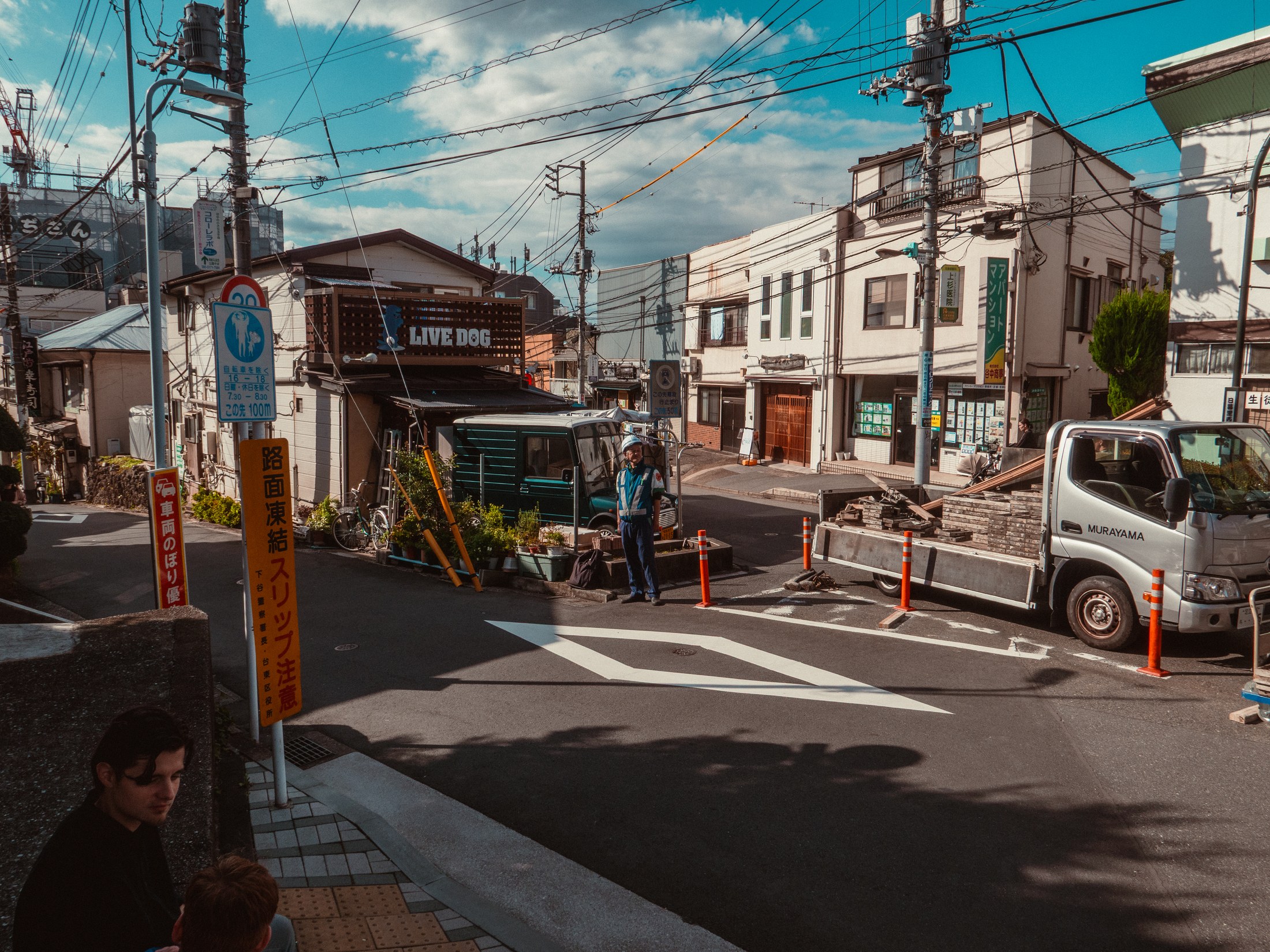 A worker standing at a neighborhood intersection beneath power lines