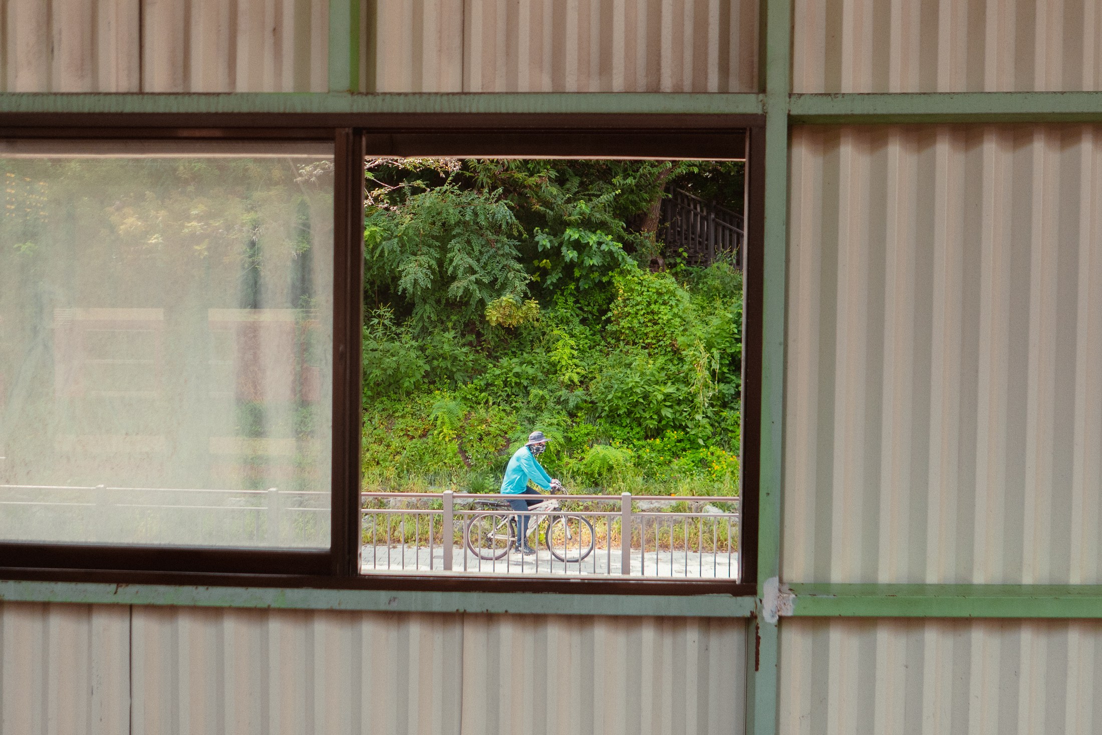 A cyclist framed through an open industrial window
