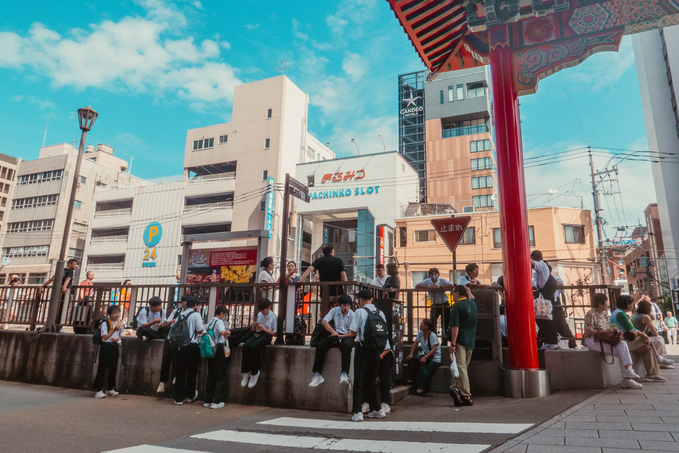 Students and pedestrians gathered near a bright red temple gate